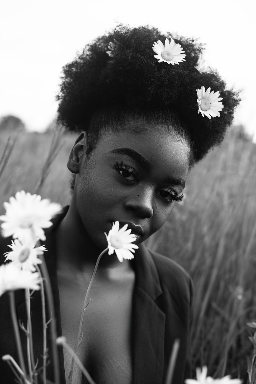 grayscale photo of woman with daisy on ear